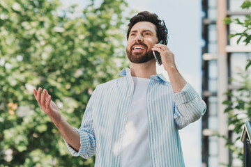 Casual Urban Lifestyle Scene of a Young Man Talking on a Mobile Phone Amidst a City Setting With...