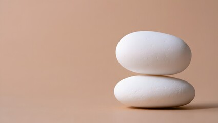 Two white zen stones stacked on a beige background for meditation and spa treatments