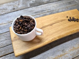 White cup with coffee beans on cutting board