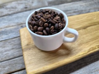 White cup with coffee beans on cutting board