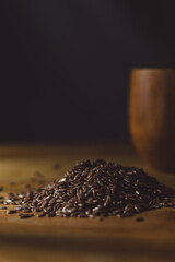 flax seeds in a wooden glass, bowl on a wooden table close-up