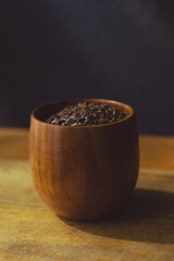 flax seeds in a wooden glass, bowl on a wooden table close-up