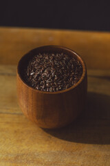 flax seeds in a wooden glass, bowl on a wooden table close-up