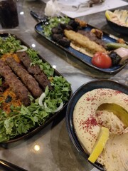 Delicious Middle Eastern mixed grill platter with kebabs, hummus, fresh herbs, and grilled vegetables served at a restaurant table