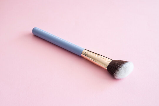 Cosmetic makeup brush on a pink background.