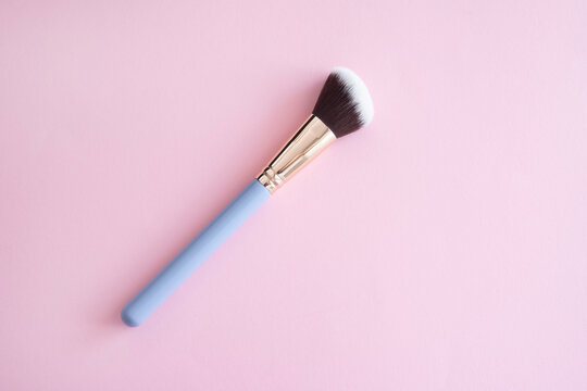 Cosmetic makeup brush on a pink background.