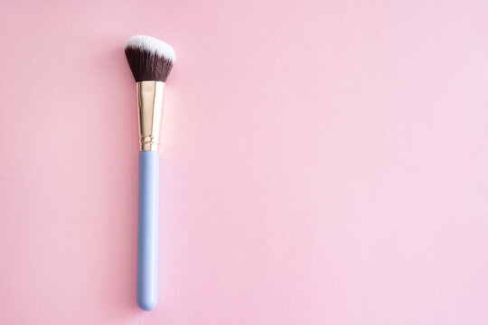 Cosmetic makeup brush on a pink background.