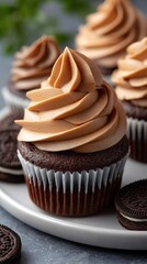 Mouthwatering chocolate Oreo cupcakes featuring creamy frosting and cookies, elegantly presented on a white plate with a grey backdrop