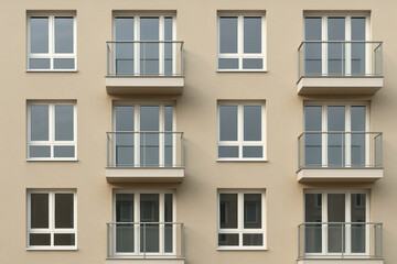 Fototapeta premium Modern urban apartment building facade with symmetrical balconies and closed windows, contemporary residential architecture exterior