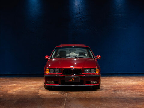 Front view of a classic red BMW 325i E36, Vintage German sports sedan under spotlights

