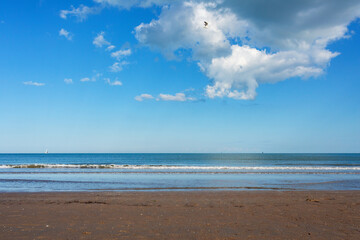 Scenic beach Sottomarina  Adriatic Sea  landscape with soft waves lapping at the shore under a bright blue sky filled with fluffy clouds, creating a serene and tranquil atmosphere for relaxation