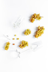 Two glasses of wine with ripe yellow grapes on white background, top view