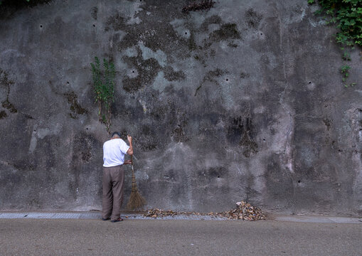 Old japanese man with a broom cleaning a road, Kyoto prefecture, Ine, Japan