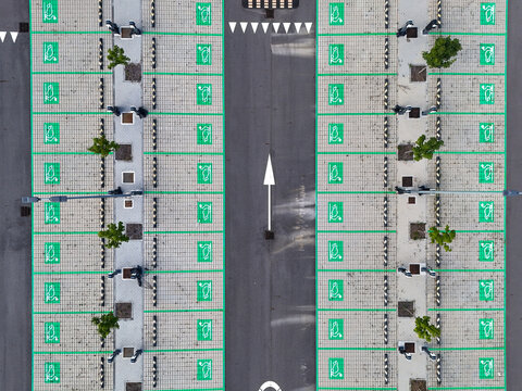 Aerial view of orderly parking spaces with vibrant green markings and small trees stand in stark contrast to the dark asphalt, creating a rhythmic pattern, Location Unknown, Location Unknown.