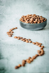 Curved line of scattered coffee beans guides the eye toward a full bowl on pale concrete, minimalist daylight scene perfect for ad copy or magazine cover layouts