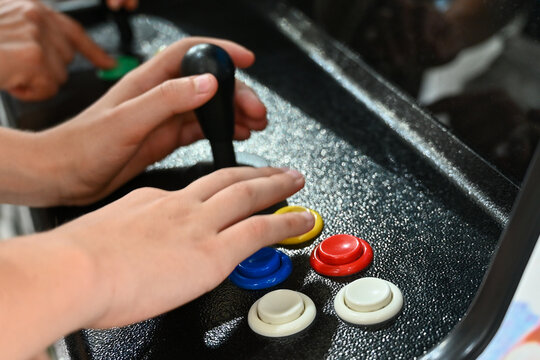 Detail on hands playing with joystick on old vintage arcade game in a dark room for playing video games