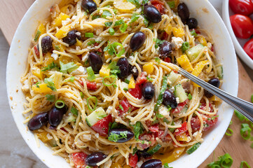 Delicious greek pasta salad with feta cheese, spaghetti noodles, peppers, cucumber, onions, tomatoes and olives, fresh and homemade cooked