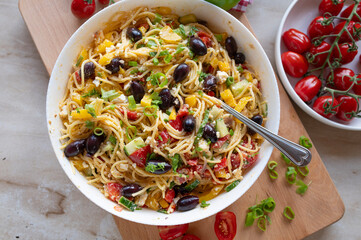 Delicious greek pasta salad with feta cheese, spaghetti noodles, peppers, cucumber, onions, tomatoes and olives, fresh and homemade cooked