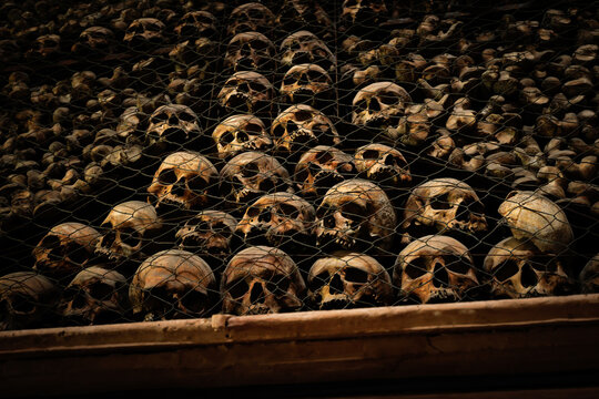Skull behind wire mesh in a dark Chapel as a symbol of transience and Memento mori - the fascination of the macabre - ossy San Bernardino alle Ossa, Milan, Italy