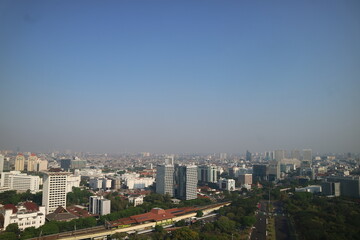 Fototapeta premium A vibrant mural depicting lush greenery and a serene landscape adorns a wall bordering a street, with a traditional wooden building visible above.