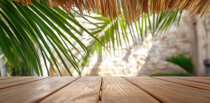 Wooden table under palm leaves and thatched roof with soft tropical lighting, perfect summer vacation or exotic travel background in natural warm tones.