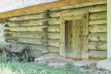 Quaint log cabin in an ancient Central European village, situated on lush green grass with a well-trodden path leading to the porch The rustic structure has horizontal logs, a raised door, potential