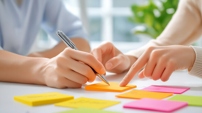 Overhead perspective of a white conference table during a creative workshop, numerous brightly colored adhesive notes with handwritten words related to strategy ,writing, note, collaborative problem-s