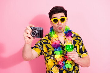 Young man enjoying a tropical vacation, holding a camera and a drink, wearing colorful lei and sunglass