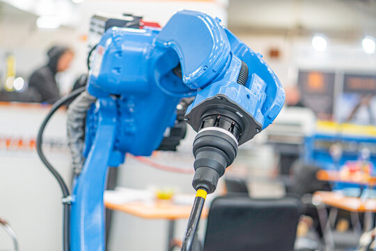 An industrial robot, predominantly blue in color, is shown within a factory setting The large-sized robot features an extendable arm and an end effector for object manipulation, possibly used for as