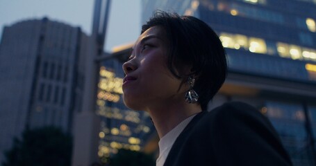 A woman stands on a city street in the evening. Close-up of her serious face