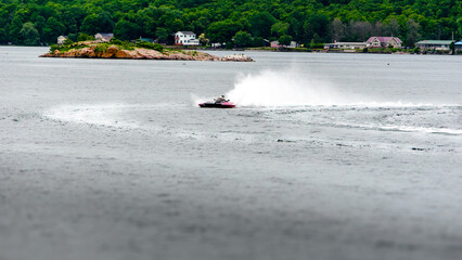 Obraz premium Single red and white hydroplane boat throwing spray on the water