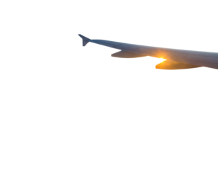 Airplane wing view from plane window over foggy mountains at sunset. Sky and sun abov .