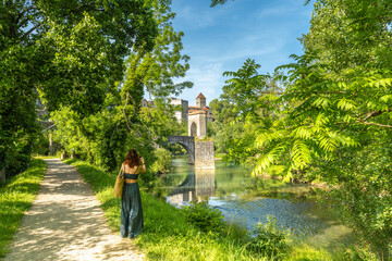 Tourist taking pictures of the medieval bridge and castle of sauveterre de bearn in france