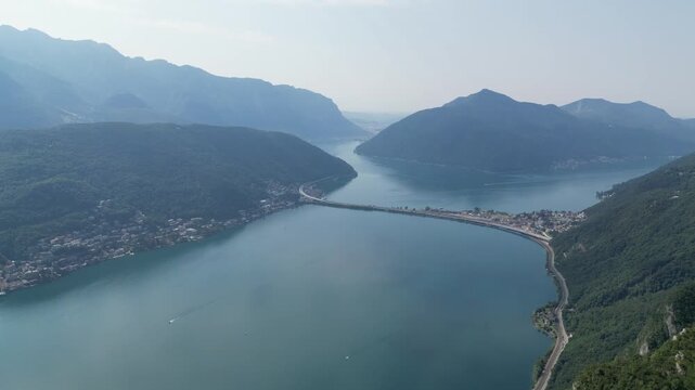 Aerial view of the Melide Causeway cutting across the tranquil waters, connecting verdant shores, Lugano, Switzerland.