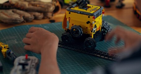 A boy builds a robot from a construction kit while sitting at a table at home. Close-up of his...