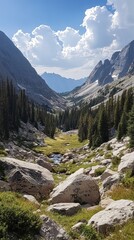 Obraz premium Majestic Mountain Valley: Stream, Boulders, and Towering Peaks Under a Cloudy Sky