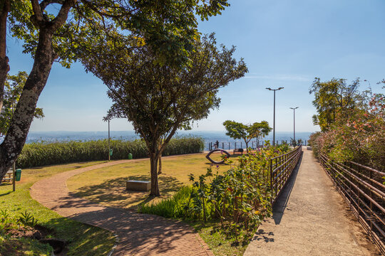 Caminho de acessibilidade com &aacute;rvores e vista para a cidade de Belo Horizonte no Mirante das Mangabeiras durante um lindo dia ensolarado
