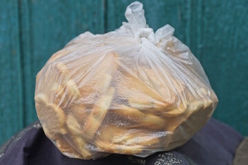 a pile of round biscuit cookies in a white cellophane bag lie on a table against the background of a green wall
