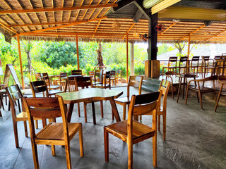 Rustic dining area in a tropical restaurant surrounded by lush greenery during midday