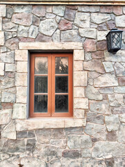 Rustic stone wall with a wooden window framed by a vintage lantern during golden hour