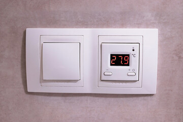 Close-up of modern wall thermostat panel for floor heating system.  Concept of smart climate control, smart home. 