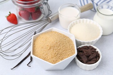 Different ingredients for panna cotta. Milk, sugar, vanilla, chocolate and strawberries on white table, closeup