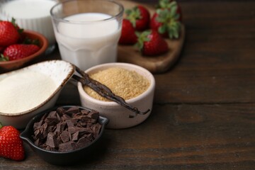 Different ingredients for panna cotta. Milk, sugar, vanilla, chocolate and strawberries on wooden table, closeup. Space for text