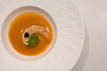 Creamy soup topped with shrimp served in a white bowl. Top view
