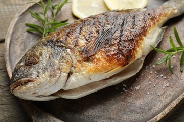 Tasty roasted dorado fish and spices on wooden table, closeup. Homemade seafood dish