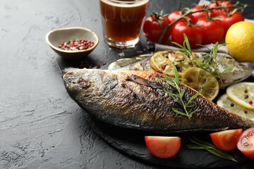Homemade seafood dish. Tasty roasted dorado fish served with beer on black table, closeup. Space for text