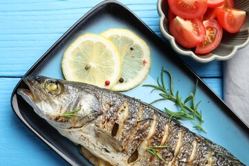 Tasty roasted seabass fish with spices and tomatoes on light blue wooden table, flat lay. Homemade seafood dish