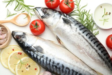 Fresh raw mackerels and spices on white table, flat lay. Seafood delicacies