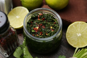 Tasty sauce with cilantro and limes on wooden table, closeup