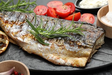 Tasty roasted mackerel served with spices and sauce on table, closeup. Homemade seafood dish